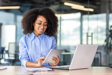 Young successful woman working with tablet computer inside office at workplace, smiling female...