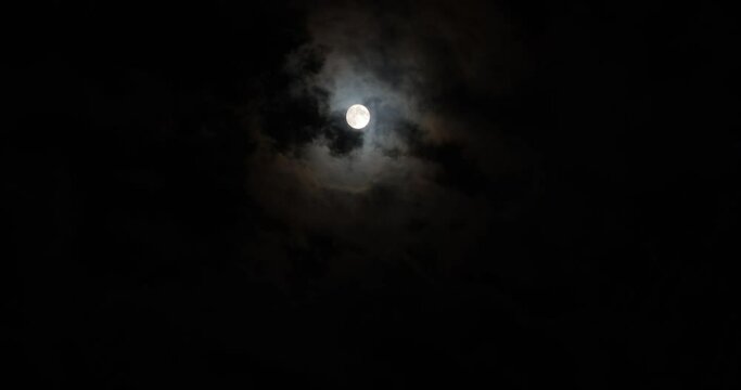 Full moon in the cloudy evening sky, time lapse