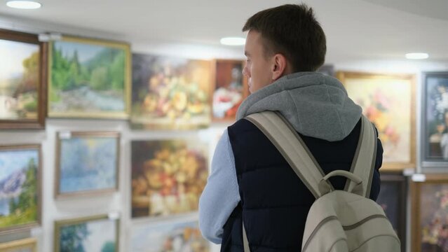 Young man looking at paintings in an art gallery