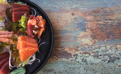 Sashimi sushi mounted on lettuce leaves on a worn background with space for text