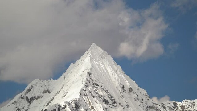 ice covered glacier of a pyramid shaped mountain at laguna paron lagoon in the high andes mountains of the cordillera blanca at huascaran, Peru, with snow covered mountain peaks on a bright sunny day.