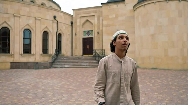 portrait of a young Arab man looking into the camera against the background of Muslim mosque