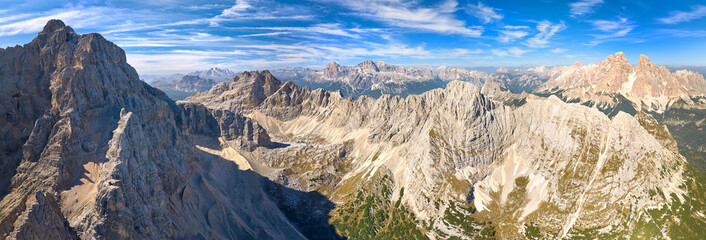 Colorful Autumn in the Dolomites. Panoramic, aerial view of the mountain massif of Punta Sorapiss peak above glacial lake Lago di Sorapiss. Sunny day, blue sky, Dolomites view from hight alltitude .