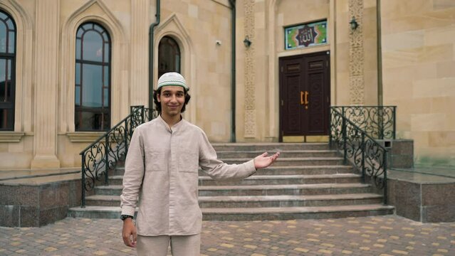 A guy of Arab appearance in national clothes with rosary around his neck prays in the courtyard of the mosque