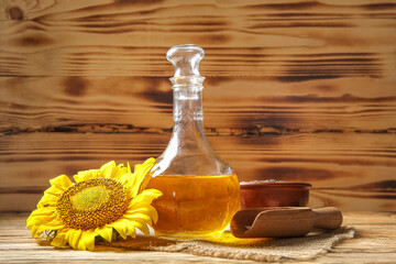 Decanter of sunflower oil, bowl and scoop with seeds on wooden background