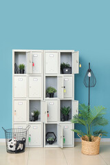 Modern locker with plants and lamp near blue wall