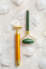 Different face massage rollers with ice cubes on light background