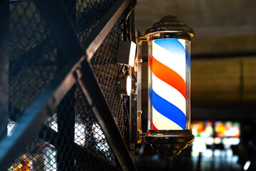 Barber pole of barbershop on vintage industrial wall in the evening. Classic barbershop spinning...