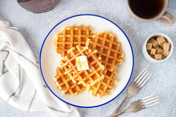 Plate of tasty waffles with maple syrup on white background