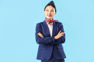 Obraz na płótnie Canvas Beautiful Asian stewardess on blue background