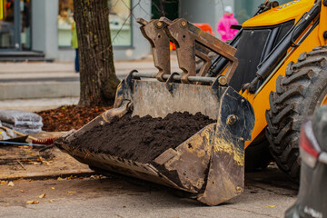 Fototapeta premium Construction earth moving equipment bucket full of earth and rocks in the construction in the city