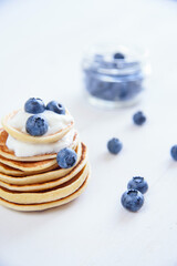 Obraz na płótnie Canvas Delicious homemade pancakes with yogurt and fresh blueberries on white wooden background.