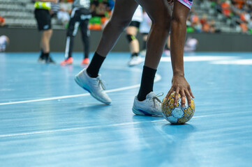 Handball woman player raises ball from parquet during the match.