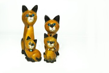 A family of four cats, wooden sculptures, dad, mom and two kittens sitting next to each other on a white background.