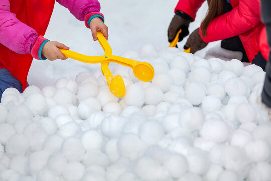 Children with yellow plastic snow ball maker for winter fun on holidays on snow