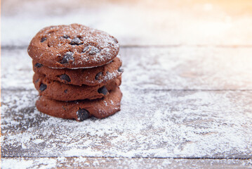 Shortbread cookies with chocolate chips on wooden background sprinkled with powdered sugar. Fresh pastry. Oatmeal cookies for dessert.