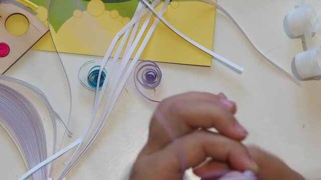 girl making paper crafts. Quilling technique. Make greeting card. Paper strips, flower, scissors. Handmade crafts on holiday: Birthday, Mother's or Father's Day, March 8, Children's DIY concept.