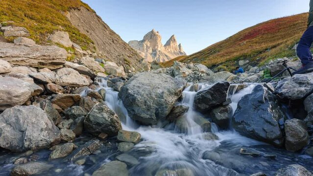 Landscape iconic three peak mountain with waterfall flowing and tourist taking pictures in valley of Aiguilles d Arves in French alps on autumn at Savoie, France