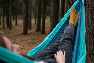 Red-haired girl lying in a hammock. A happy young woman resting in an autumn forest.