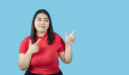 Obraz na płótnie Canvas Portrait girl young woman asian chubby fat cute beautiful pretty one person wearing a red shirt is sitting, looking smiling happily holding copyspace imaginary on the isolated blue color background