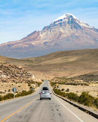 carro trafegando em rodovia com cordilheira dos andes ao fundo, na Bolívia 