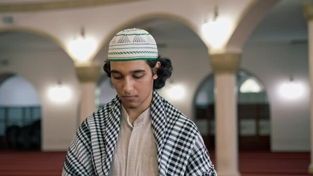 Close-up portrait of an Arab guy in national clothes with a rosary around his neck praying in courtyard of the mosque