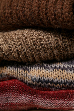 Close of image pile of knitted wool sweaters. Winter autumn cozy season concept.