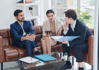 Portrait business team woman girl and man Asian group teamwork meeting sitting on sofa looking hand holding laptop notebook talk and propose ideas working for new project inside home office.