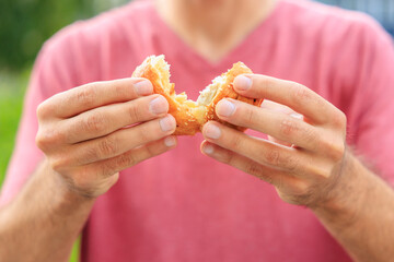 A guy's hand holds a mini puff pastry with cheese, snack and fast food concept. Selective focus on hands