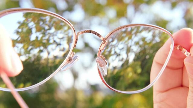glasses with dirty lenses in female hands, individuals with poor vision adapt lifestyle choices and habits accommodate visual needs, Eyeglass Fashion