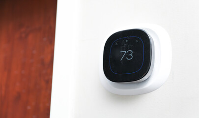 thermostat on a modern wall, symbolizing climate control and energy efficiency in a cozy home