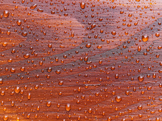full frame natural background with rain drops on red wooden table