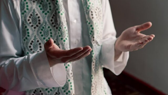 Close-up shot of a Muslim man's hands praying on his knees during Ramadan in Islamic temple