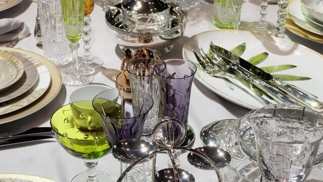 Table set for a banquet with glasses for various alcohols, plates, cutlery, crystal fruit bowls