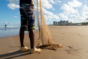 Fishermen are seen fishing on the beach of Jaguaribe in the city of Salvador, Bahia. - obrazy, fototapety, plakaty