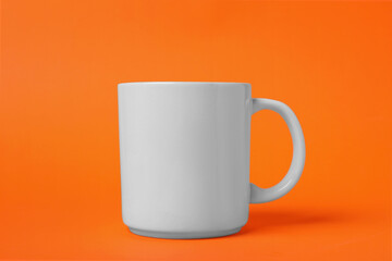 One white ceramic mug on orange background