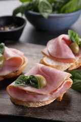 Delicious sandwiches with ham, basil and olives on table, closeup