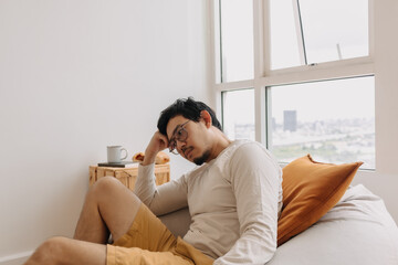 Asian man thinking and missing sits on bean bag and relaxed in weekend.