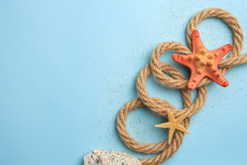 Beautiful sea stars, rope and sand on light blue background, flat lay. Space for text