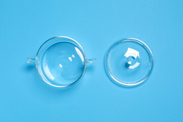 Empty glass pot and lid on light blue background, flat lay