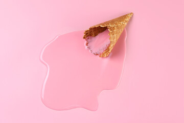 Melted ice cream and wafer cone on pink background, top view. Space for text