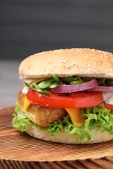 Delicious burger with tofu and fresh vegetables on wooden board, closeup
