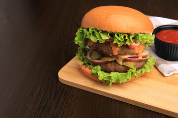 Board of tasty burger served with ketchup on wooden table. Space for text