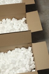 Many open cardboard boxes with pieces of polystyrene foam on grey floor
