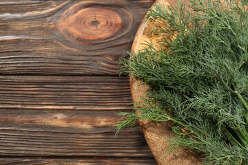 Bunch of fresh green dill on wooden table, top view. Space for text