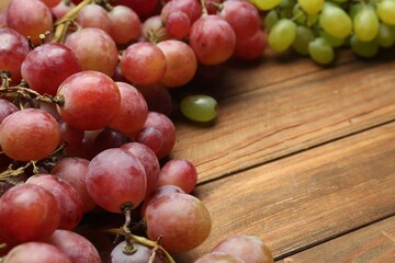 Different fresh ripe grapes on wooden table, closeup. Space for text
