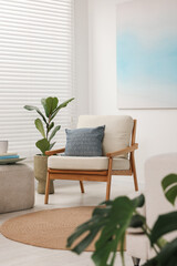 Comfortable beige armchair and houseplant in living room. Interior design