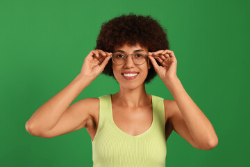 Portrait of happy young woman in eyeglasses on green background