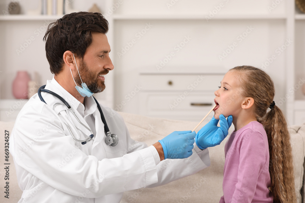 Canvas Prints Smiling doctor examining girl`s oral cavity with tongue depressor indoors