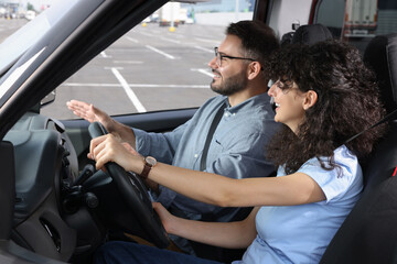 Driving school. Happy student during lesson with driving instructor in car at parking lot